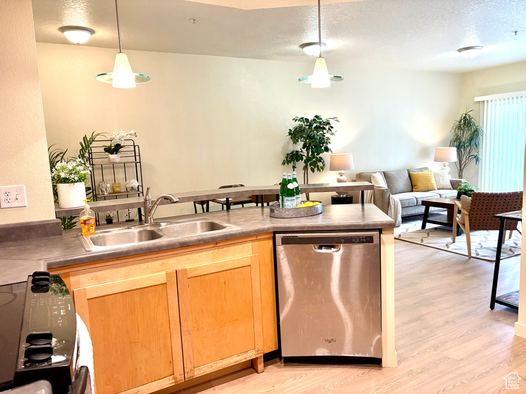 Kitchen featuring stainless steel dishwasher, light wood-style floors, a textured ceiling, pendant lighting, and black range oven