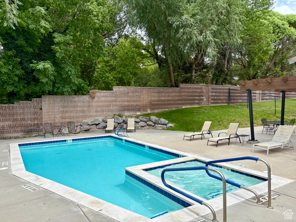 Community pool with a community hot tub, a patio, and view of wooded area