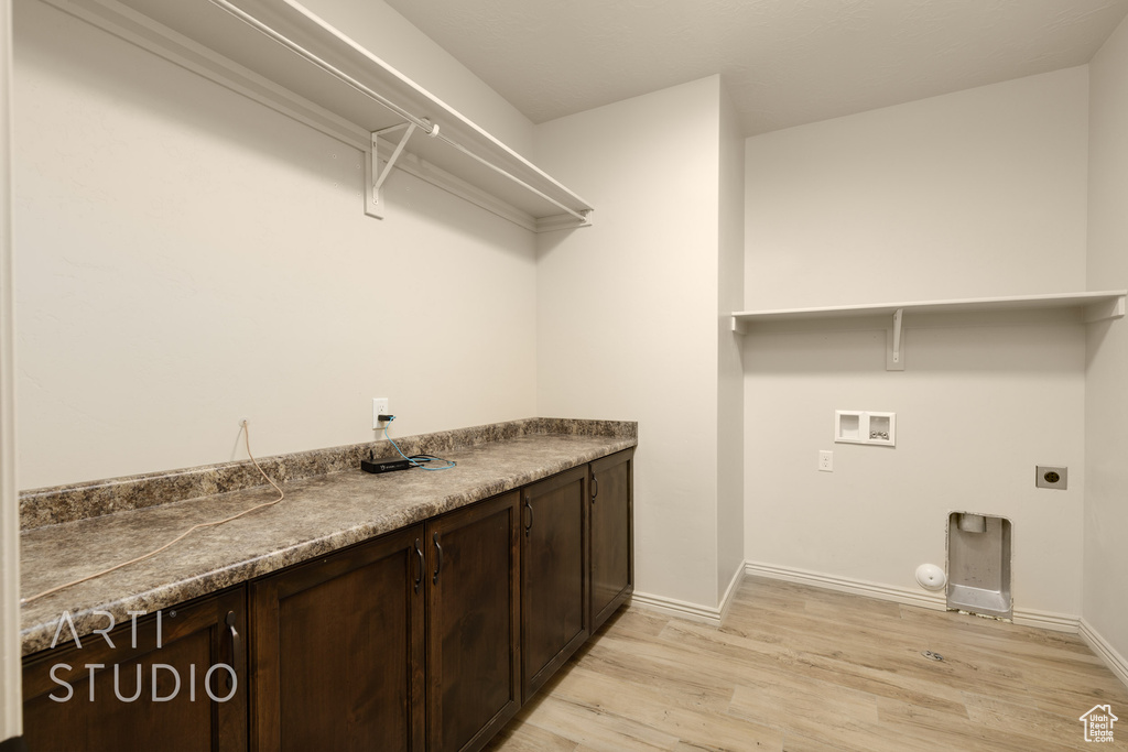 Washroom with hookup for an electric dryer, light wood finished floors, hookup for a washing machine, cabinet space, and hookup for a gas dryer