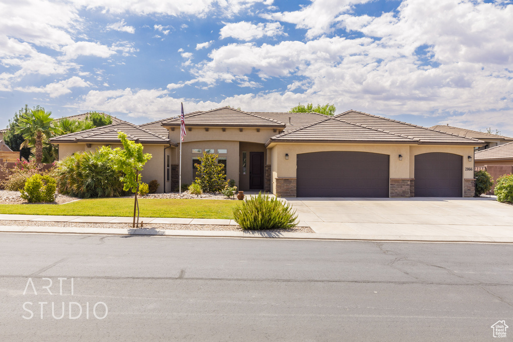 Mediterranean / spanish-style home with a garage, concrete driveway, a front lawn, stucco siding, and stone siding