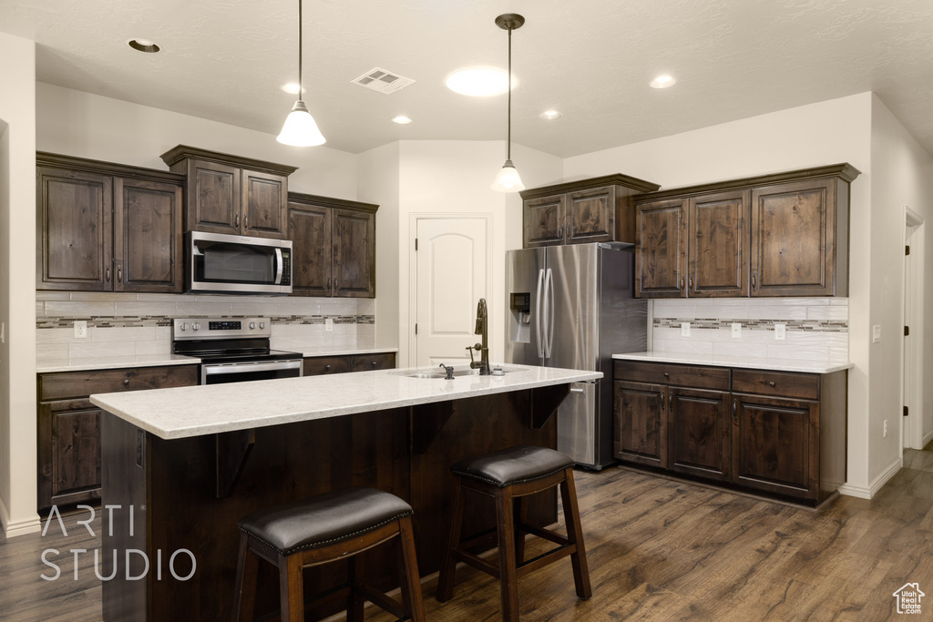 Kitchen with appliances with stainless steel finishes, tasteful backsplash, light countertops, dark wood-style flooring, and recessed lighting