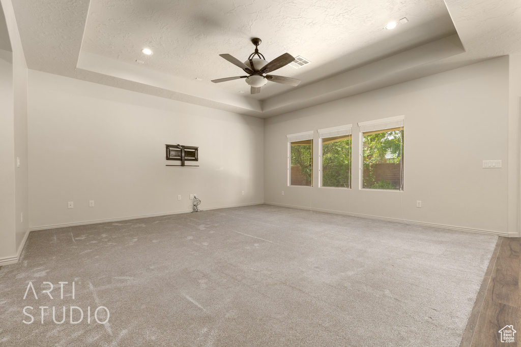Carpeted empty room featuring a tray ceiling, ceiling fan, a textured ceiling, and recessed lighting
