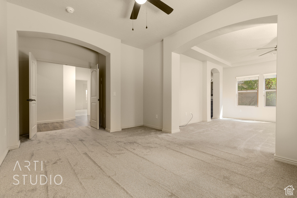 Spare room with ceiling fan, arched walkways, and carpet