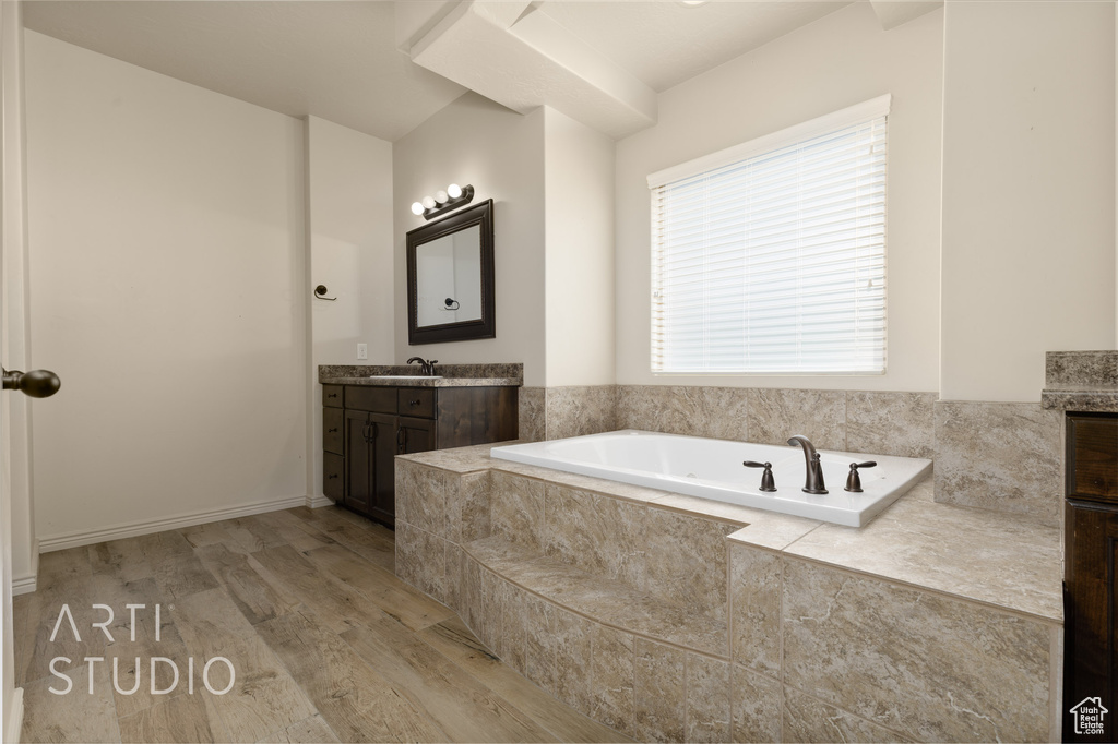 Full bathroom with vanity, a garden tub, and wood finished floors