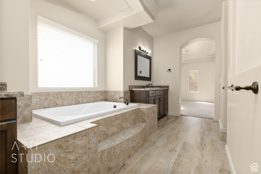 Bathroom featuring vanity, a garden tub, and wood finished floors