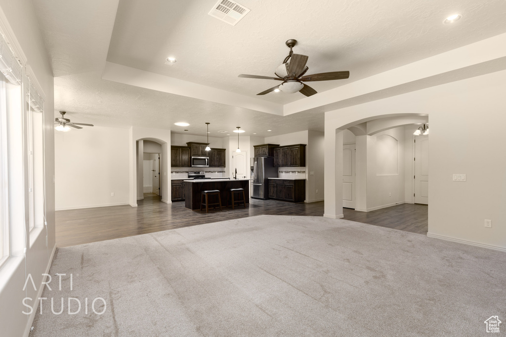 Unfurnished living room featuring arched walkways, ceiling fan, carpet flooring, and recessed lighting
