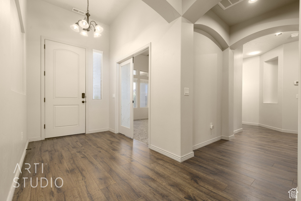 Foyer featuring dark wood finished floors, arched walkways, and a chandelier