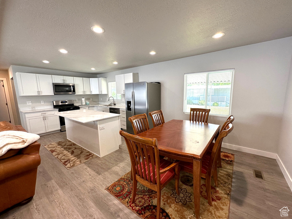 Dining room featuring a textured ceiling, plenty of natural light, dark wood-type flooring, and recessed lighting