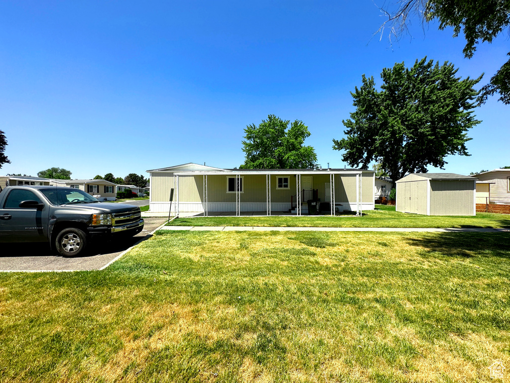 View of front of home featuring a storage shed and a front lawn