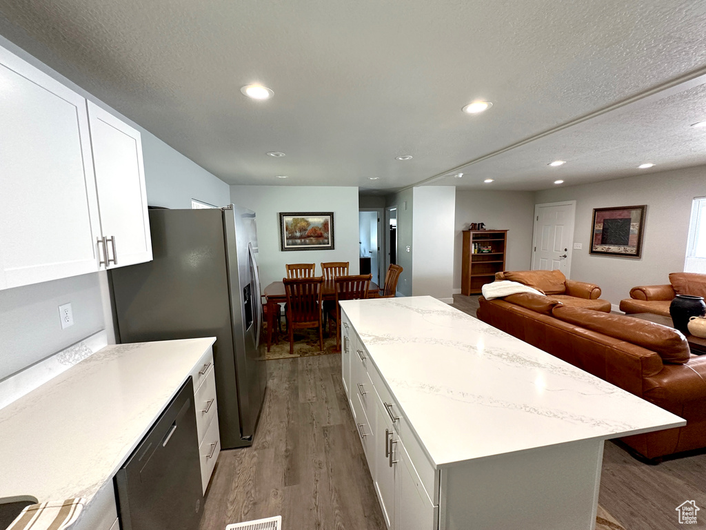Kitchen featuring wood finished floors, open floor plan, a center island, stainless steel fridge with ice dispenser, and recessed lighting