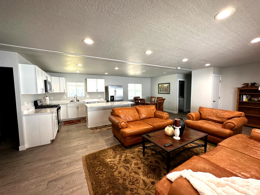 Living room with a textured ceiling, recessed lighting, and wood finished floors