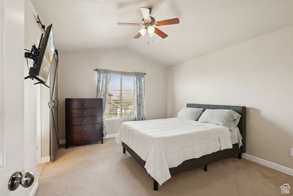 Bedroom with light colored carpet, lofted ceiling, and a ceiling fan