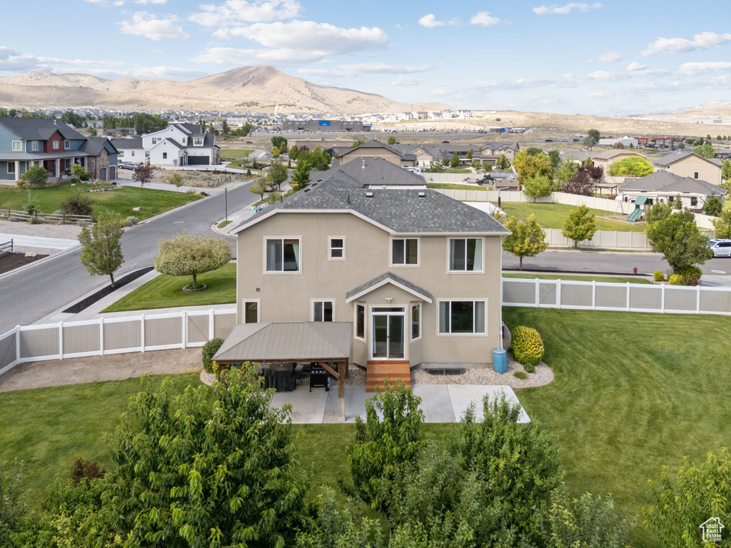 Back of house featuring a fenced backyard, a mountain view, a residential view, stucco siding, and a gazebo