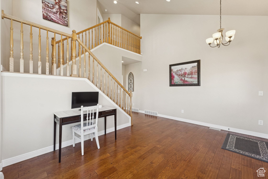 Living room featuring wood finished floors, stairs, a chandelier, recessed lighting, and a high ceiling