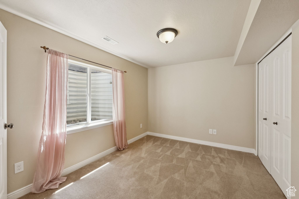 Unfurnished bedroom with light colored carpet and a closet