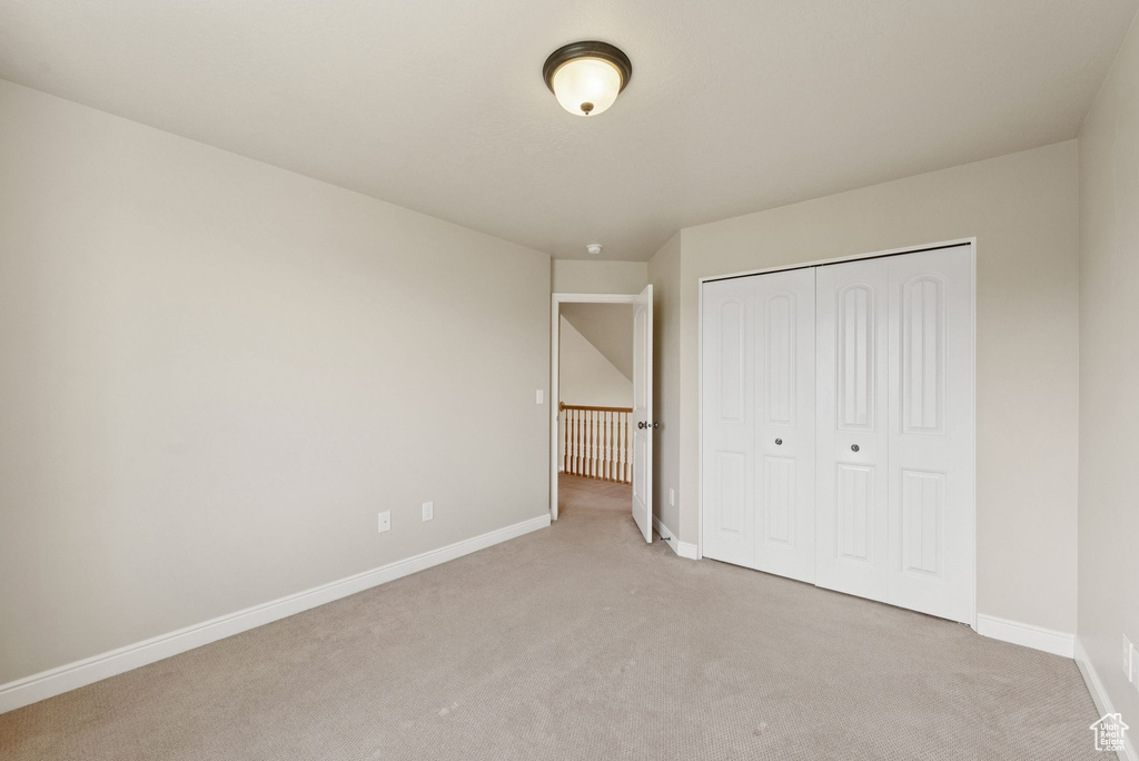 Unfurnished bedroom with light colored carpet and a closet