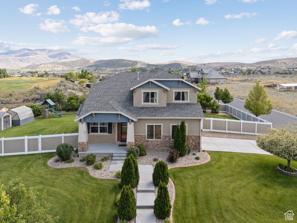 View of front of house with stone siding, a mountain view, a shingled roof, stucco siding, and a porch