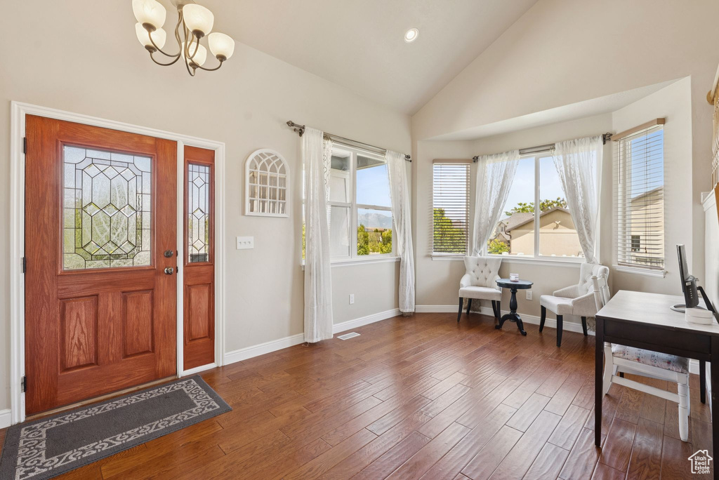Entryway with a chandelier, wood finished floors, and high vaulted ceiling
