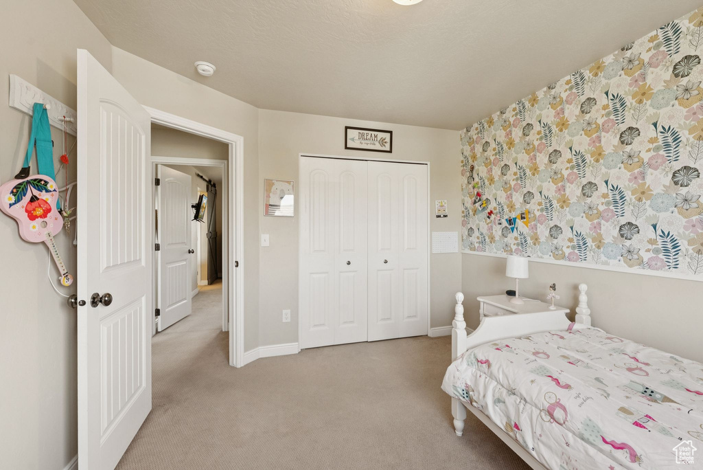 Carpeted bedroom featuring a closet and baseboards