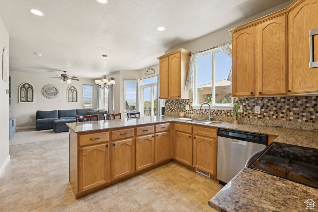 Kitchen with dishwasher, a peninsula, open floor plan, backsplash, and a chandelier