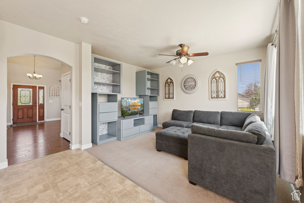 Living room with arched walkways, ceiling fan, and a chandelier