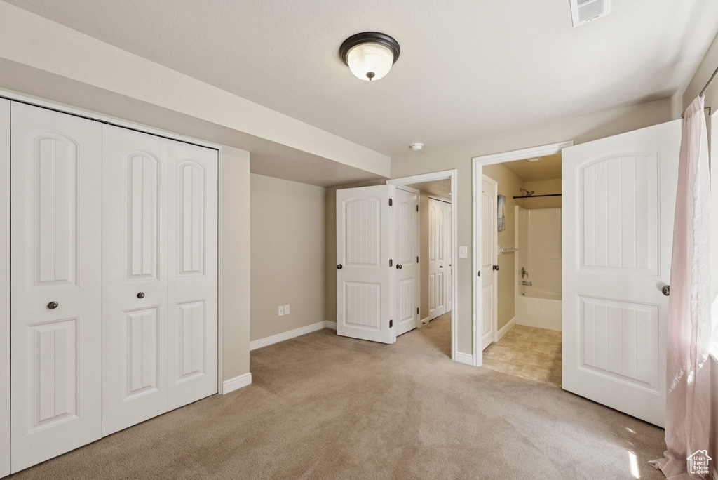 Unfurnished bedroom with light colored carpet, a closet, and connected bathroom