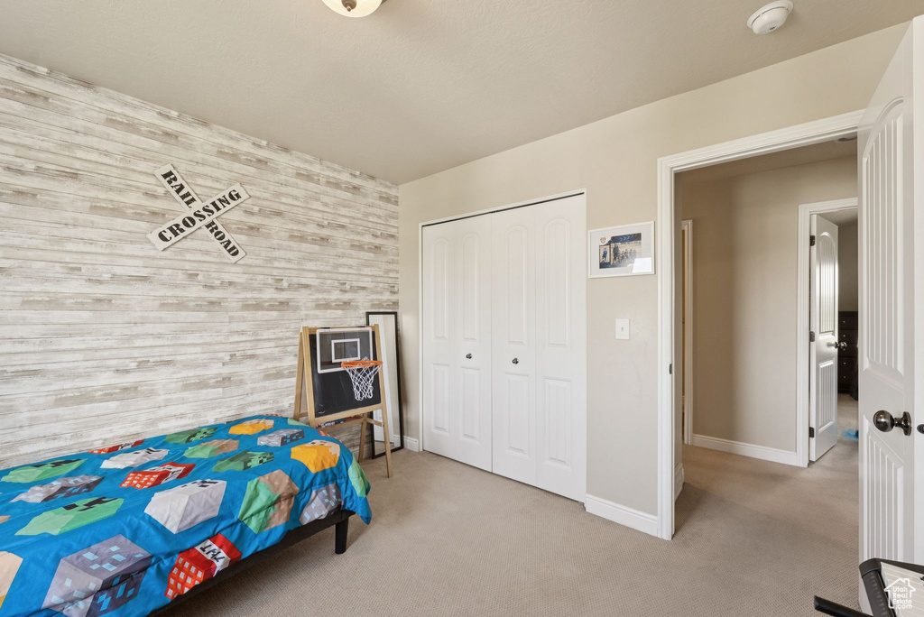 Bedroom featuring an accent wall, wood walls, carpet, and a closet