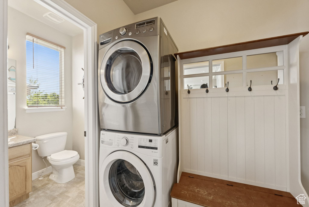 Washroom featuring stacked washer and clothes dryer and baseboards