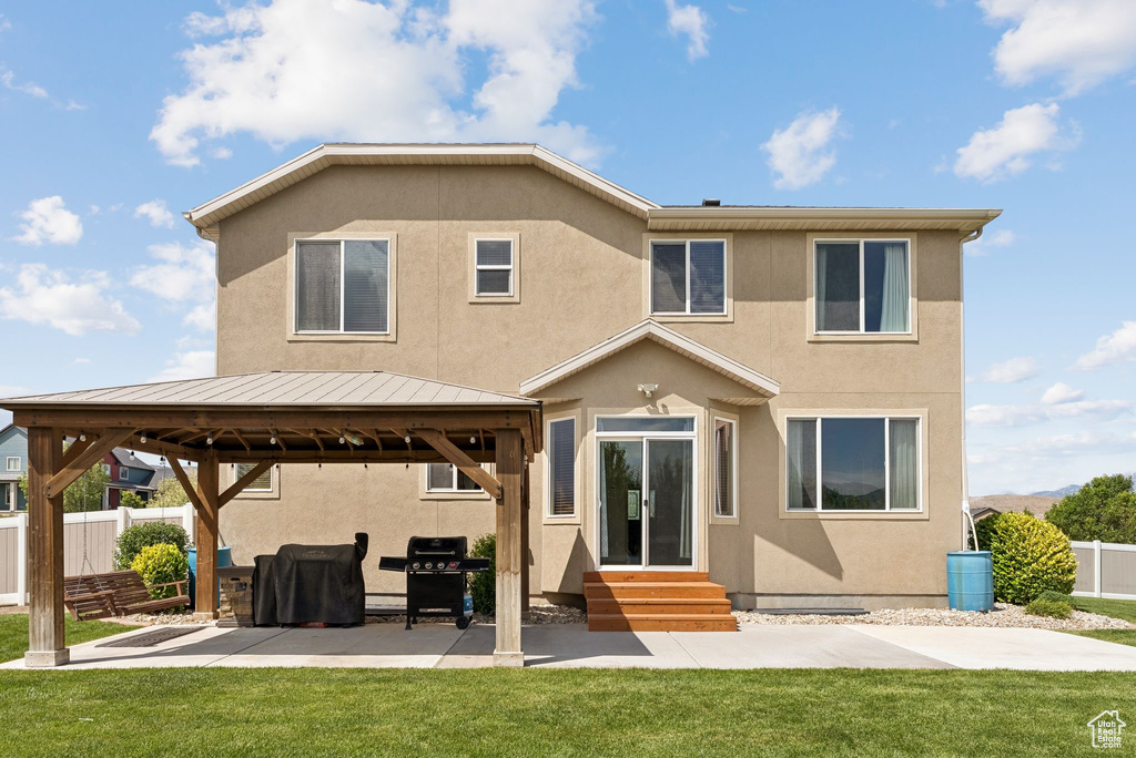 Rear view of property featuring entry steps, a gazebo, stucco siding, a standing seam roof, and a patio
