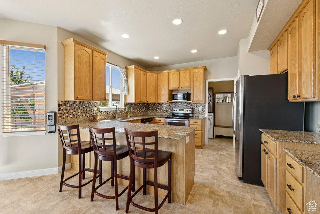 Kitchen with appliances with stainless steel finishes, a peninsula, plenty of natural light, backsplash, and recessed lighting