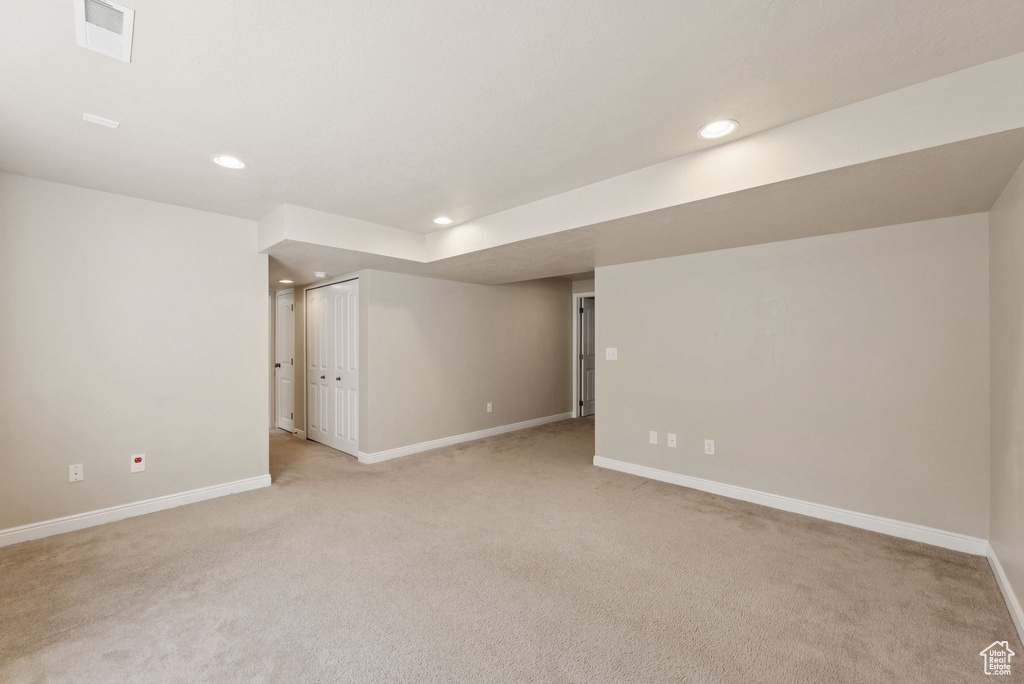Finished below grade area with light colored carpet and recessed lighting