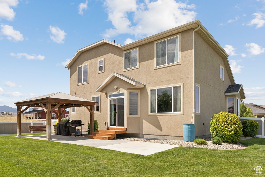 Rear view of house featuring a gazebo, stucco siding, and a patio area