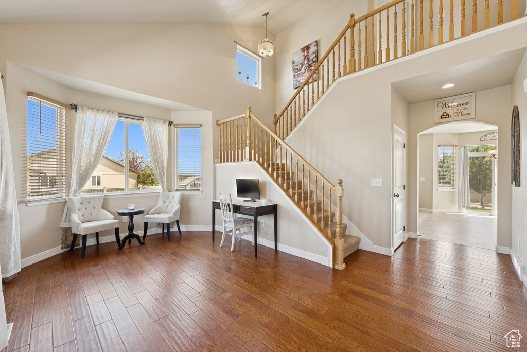 Sitting room featuring arched walkways, high vaulted ceiling, hardwood / wood-style flooring, and stairway