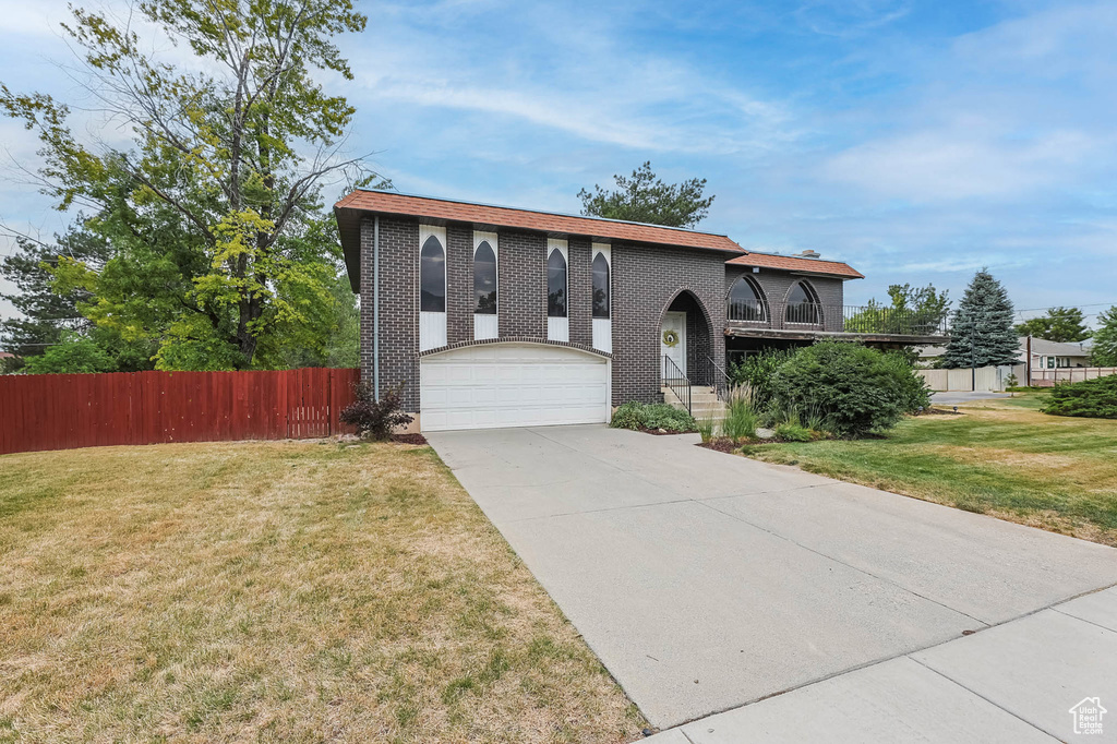 Split foyer home with brick siding, concrete driveway, and a garage