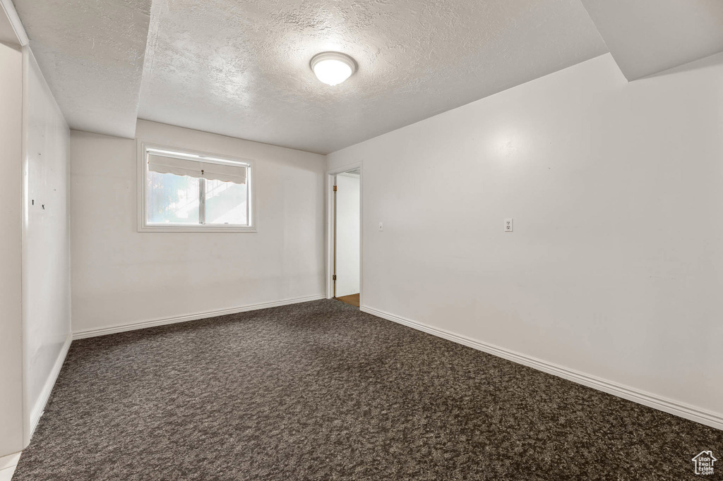 Carpeted empty room featuring a textured ceiling and baseboards