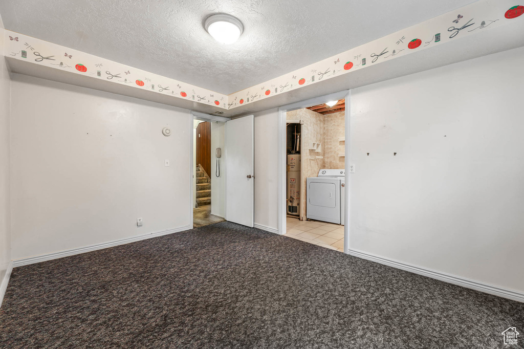 Unfurnished bedroom with light colored carpet, a textured ceiling, water heater, and washer and clothes dryer