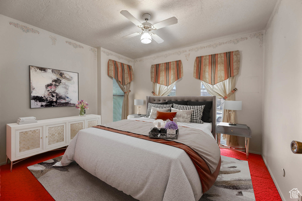 Carpeted bedroom with multiple windows, a textured ceiling, and a ceiling fan