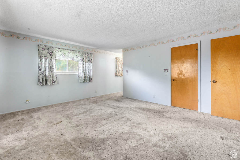Carpeted empty room featuring a textured ceiling