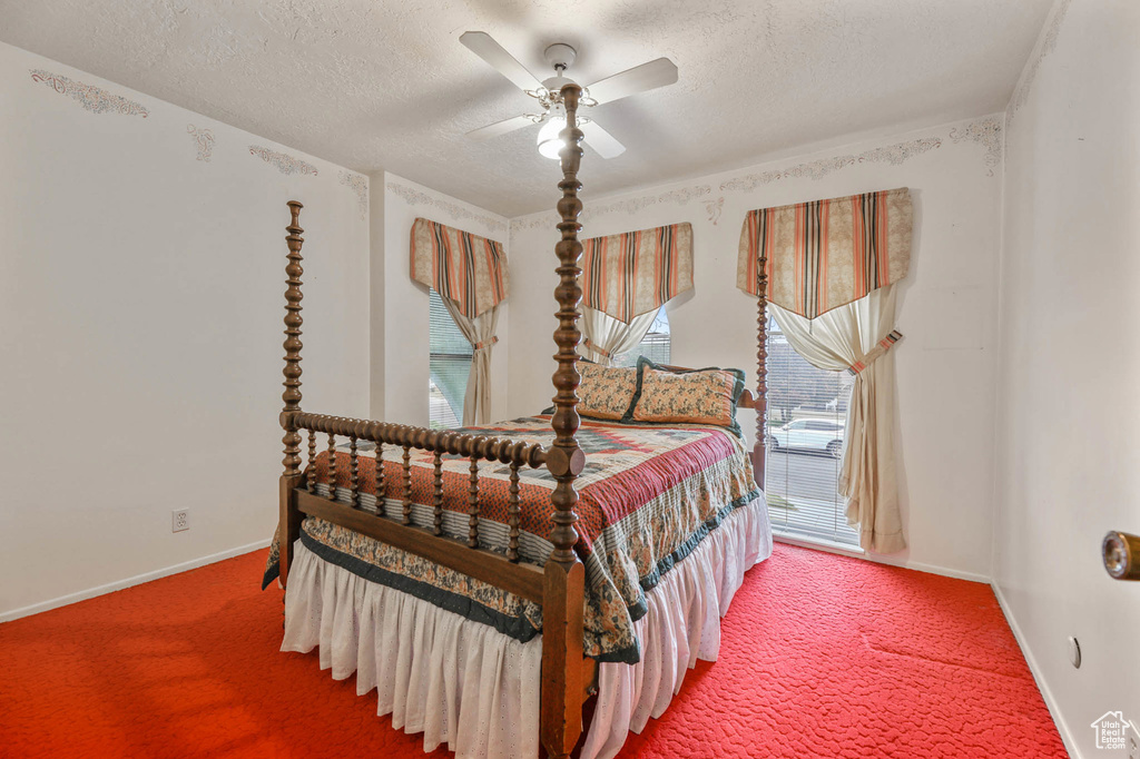 Bedroom featuring carpet, multiple windows, a textured ceiling, and a ceiling fan