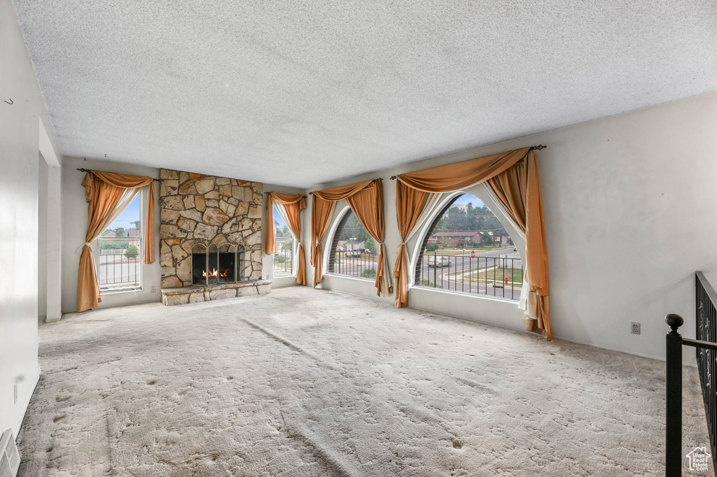 Unfurnished living room with a textured ceiling, carpet flooring, and a fireplace