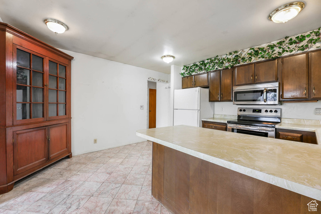 Kitchen with appliances with stainless steel finishes, light countertops, and glass insert cabinets