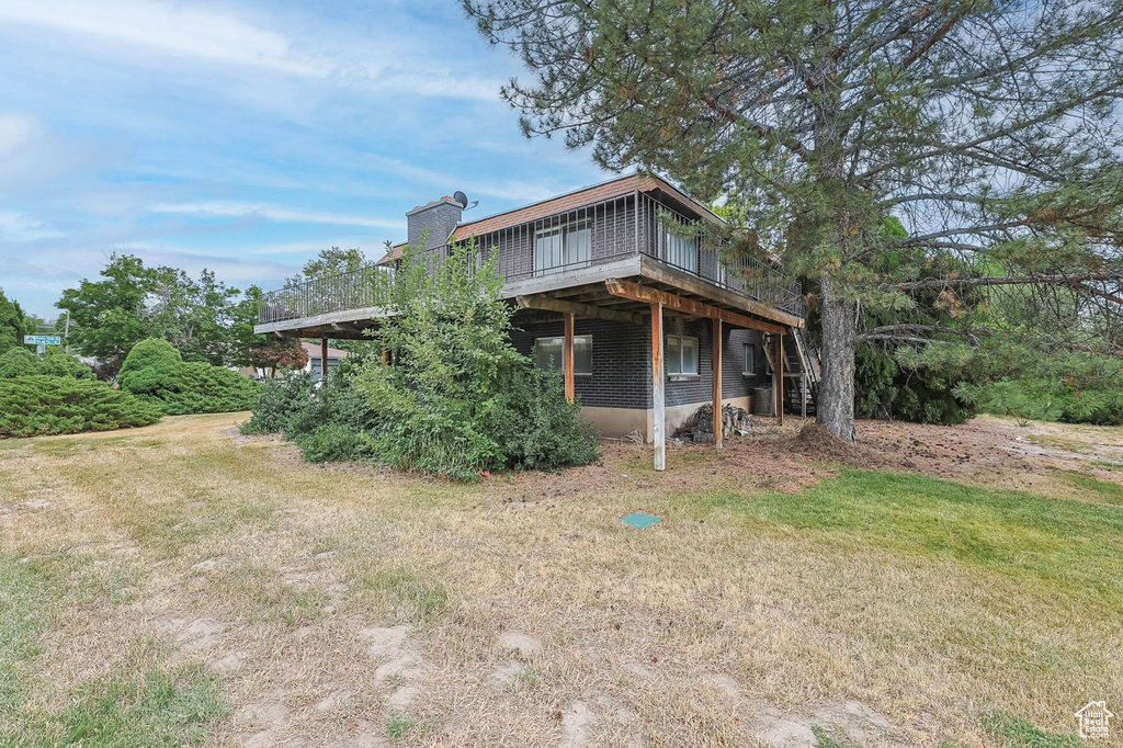 Back of property featuring a deck, a chimney, and a lawn