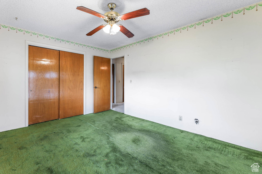 Unfurnished bedroom featuring carpet floors, a closet, a textured ceiling, and ceiling fan