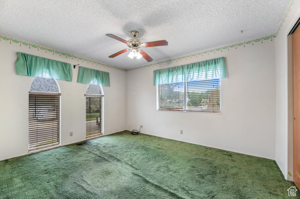 Carpeted spare room featuring ceiling fan and a textured ceiling