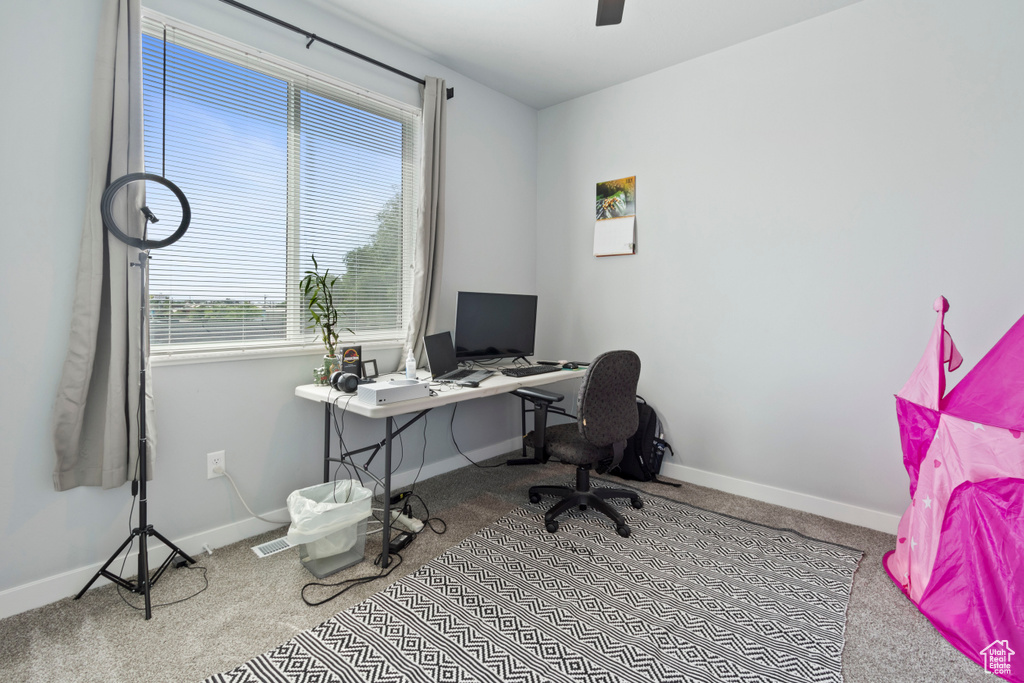 Carpeted office space featuring baseboards and ceiling fan