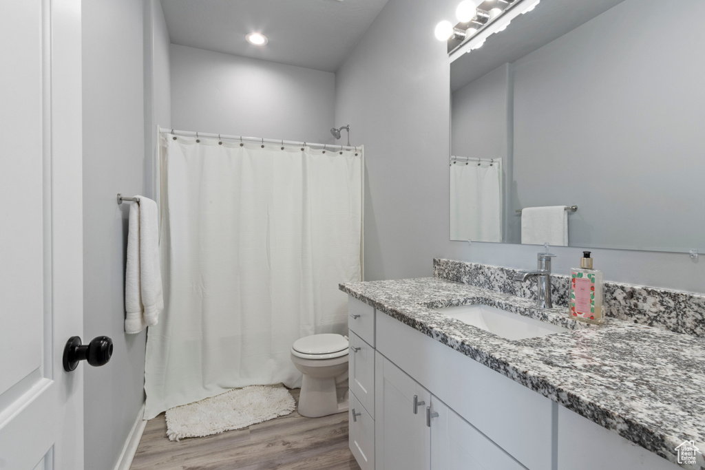 Bathroom featuring vanity, wood finished floors, shower / bath combo with shower curtain, and recessed lighting