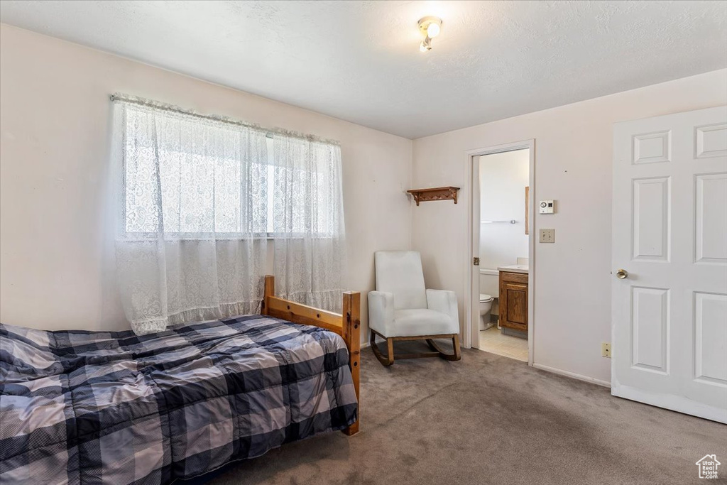 Carpeted bedroom featuring connected bathroom and baseboards