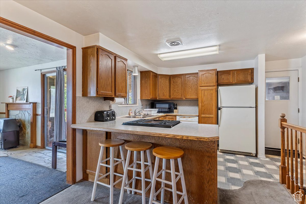 Kitchen featuring white appliances, plenty of natural light, light countertops, and a textured ceiling