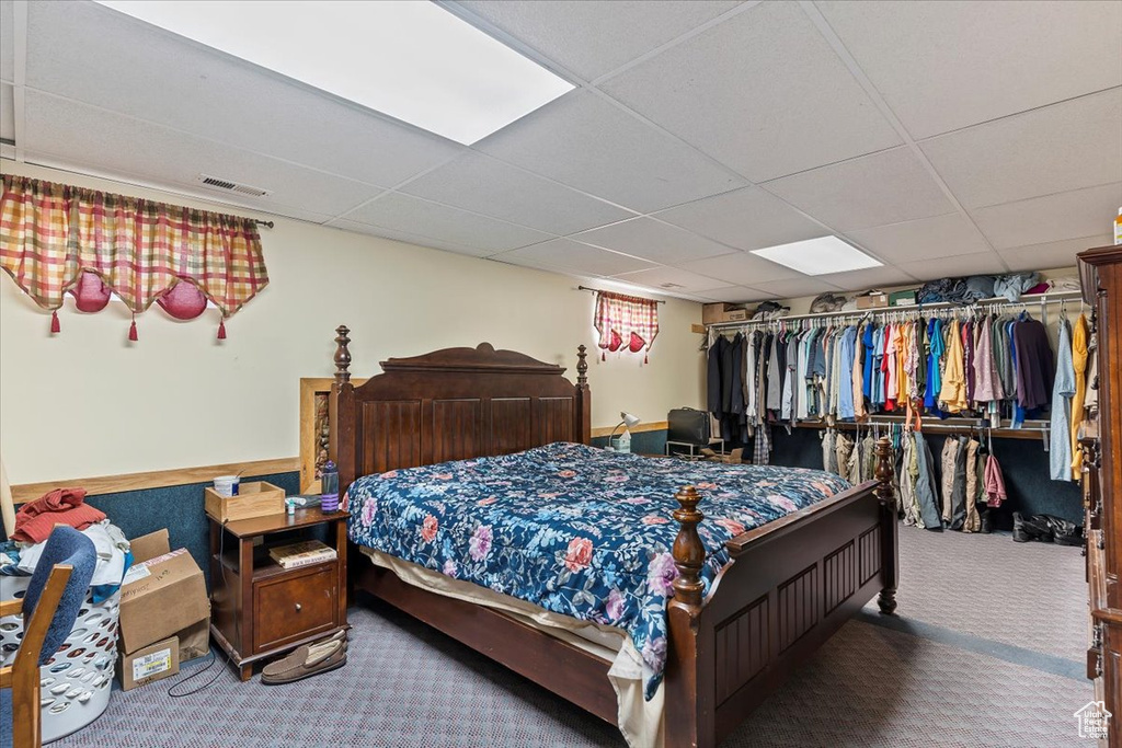 Carpeted bedroom with a paneled ceiling and a closet