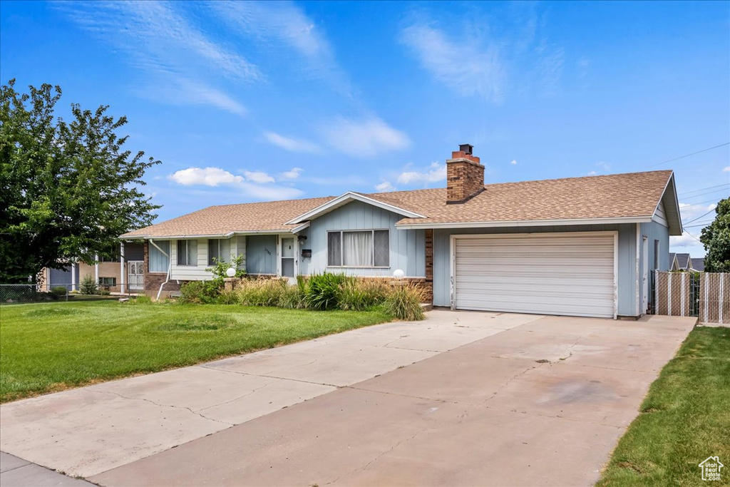 Single story home with a chimney, a garage, driveway, and a shingled roof
